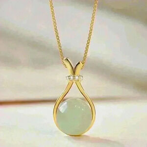 Jade Stone encased in a sleek gold necklace, accented with a sparkling c…